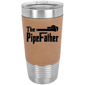 May include: A stainless steel travel mug with a brown leatherette wrap. The mug has a black graphic of a wrench and the text "The PipeFather".