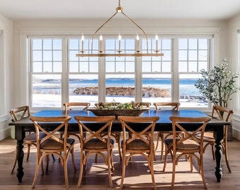 May include: A dining room with a large wooden table and chairs, a chandelier, and large windows overlooking a snowy waterfront.