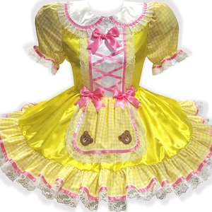 Yellow dress with pink ribbon bows and teddy bear appliques on a white background