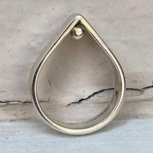 Peut inclure: Une bague en argent en forme de larme avec une petite perle ronde au centre.