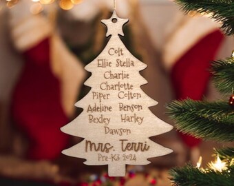 May include: Wooden Christmas tree ornament with the names Colt, Ellie, Stella, Charlie, Charlotte, Piper, Colton, Adeline, Benson, Bexley, Harley, Dawson, and Mrs. Terri, along with the text "Pre-K3 2024".