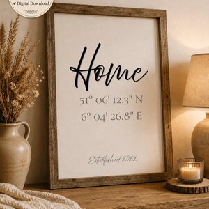 May include: A rectangular wall art print in a rustic wooden frame featuring the word Home in black script, followed by the coordinates 51° 06' 12.3" N and 6° 04' 26.8" E, with the text Established 2022 at the bottom on a light background.