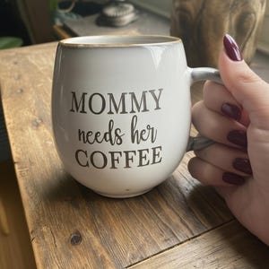 May include: A set of three ceramic mugs with a speckled, matte finish. The mugs are in shades of cream, light gray, and dark gray. Each mug has a simple, minimalist design and a rounded handle.
