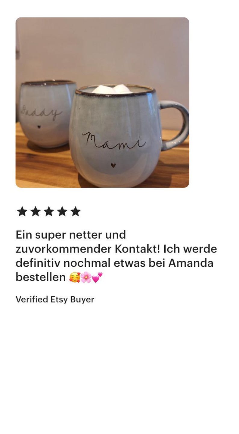 K&ouml;nnte beinhalten: Zwei hellblaue Keramiktassen mit dunklem Rand und Henkel. Auf der Vorderseite der Tassen steht der handgeschriebene Text Mami und Daddy in schwarzer Schrift, jeweils mit einem kleinen schwarzen Herzsymbol unter dem Text. Die Tassen sind mit wei&szlig;em Schaum gef&uuml;llt.
