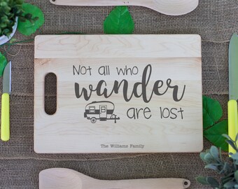 May include: A wooden cutting board with the text "Not all who wander are lost" and a small camper illustration. The text "The Williams Family" is also engraved on the board.