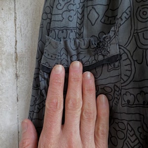 May include: Gray skirt with a black and white geometric pattern. The skirt has a small tear in the fabric.