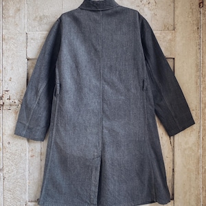 May include: A dark gray long-sleeved jacket with a collar and a single button closure. The jacket has a straight fit and a slightly longer length.