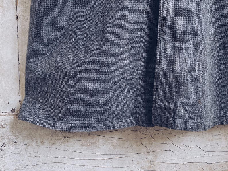 May include: A dark gray denim skirt with a button closure. The skirt has a straight silhouette and a simple design.
