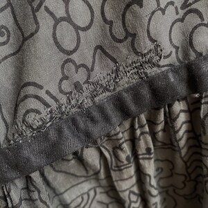 May include: A gray skirt with a black waistband and a black and white abstract pattern.