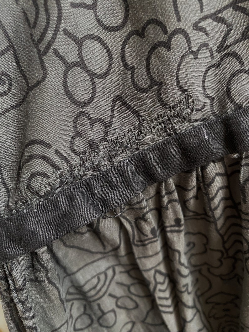 May include: A gray skirt with a black waistband and a black and white abstract pattern.