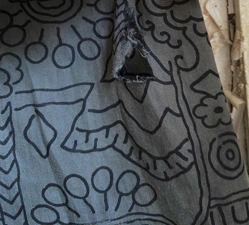 May include: A gray fabric with a black and white abstract pattern. The fabric has a tear in the upper right corner.