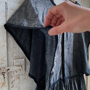 May include: A gray and black patterned dress with a gathered skirt and short sleeves. The dress has a black trim around the neckline and sleeves.