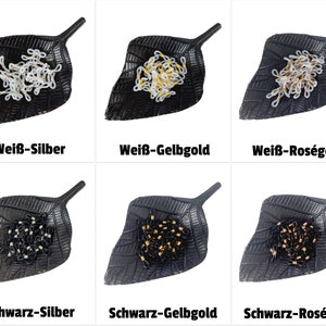 Könnte beinhalten: Sechs kleine Schalen, jede in Form eines Blattes, enthalten einen Haufen kleiner, miteinander verbundener Ketten. Die Ketten sind in verschiedenen Farben, darunter Weiß, Schwarz und Gold. Die Schalen befinden sich auf einem weißen Hintergrund. Der Text unter jeder Schale beschreibt die Farbe der Kette und das Metall, aus dem sie besteht. Der Text lautet: "Weiß-Silber", "Weiß-Gelbgold", "Weiß-Roségold", "Schwarz-Silber", "Schwarz-Gelbgold" und "Schwarz-Roségold".