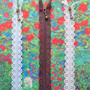 May include: Three zipper closures with decorative lace trim. The zippers are white, brown, and white. The zippers are on a colorful floral fabric background.