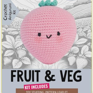 May include: A crochet amigurumi kit for a pink strawberry character with a green top, black eyes, and a smiling mouth. The packaging features the text "Strawberry," "The Knitty Critters Collection," "Fruit & Veg," and lists included materials.