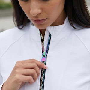 May include: A white long-sleeved jacket featuring a full-length front zip with a metallic rainbow-coloured finish. The jacket has a high collar and raglan sleeves. The text "Jackets with style" is printed in black across the lower portion.