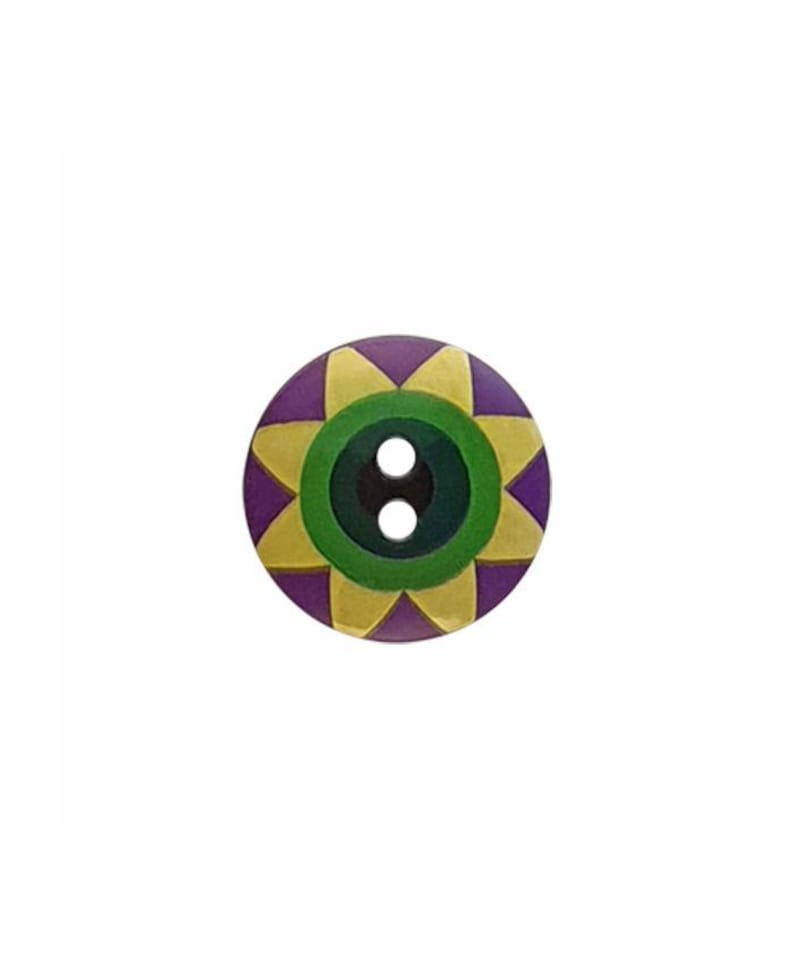 May include: A round, two-hole button featuring a central dark green circle surrounded by a yellow star-shaped pattern on a purple background. The design is symmetrical, with the yellow points extending toward the outer edge of the circular button.