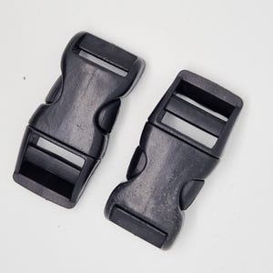 May include: Two black plastic side release buckles. The buckles are designed to be used with webbing or straps.