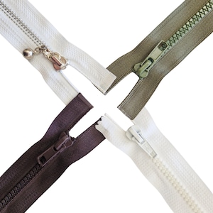 May include: Four different coloured zippers: white, olive green, dark brown, and off-white. Each zipper is partially open, showing the teeth and the slider. The white zipper has a decorative pull with a small silver ball.