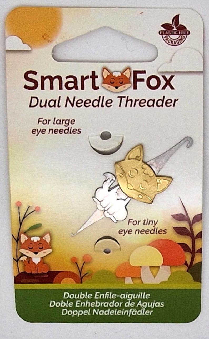 May include: A Smart Fox dual needle threader package. The packaging features a gold-coloured fox-shaped needle threader, designed for both large and tiny eye needles. The packaging has a nature-themed illustration with a fox and mushrooms.