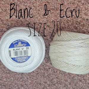 May include: Two spools of DMC embroidery floss, one white and one ecru, both size 20. The white spool has a blue label with the text "Made in France DMC BLANC N&deg; 20 077840075402 CORDONNET SPECIAL".