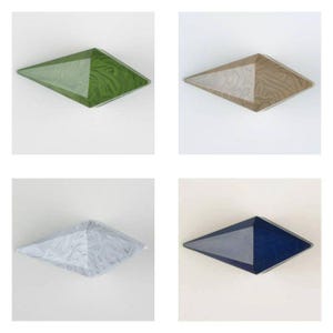 May include: Four diamond-shaped objects with faceted surfaces. One is green with a swirling pattern, one is tan with a marbled texture, one is white with a grey marbled design, and one is dark blue with a smooth, solid-colored finish.