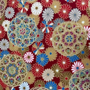 Puede incluir: Tela roja con un patr&oacute;n repetitivo de flores estilizadas doradas, azules y blancas. Las flores est&aacute;n dispuestas en un patr&oacute;n circular y tienen un dise&ntilde;o delicado e intrincado.