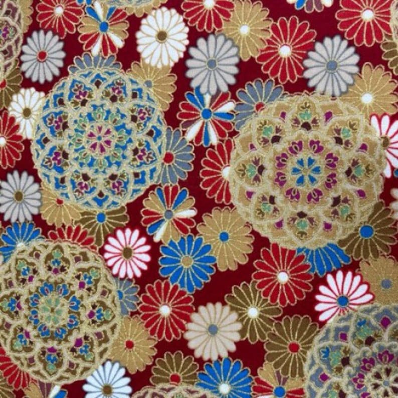 Puede incluir: Tela roja con un patr&oacute;n repetitivo de flores estilizadas doradas, azules y blancas. Las flores est&aacute;n dispuestas en un patr&oacute;n circular y tienen un dise&ntilde;o delicado e intrincado.