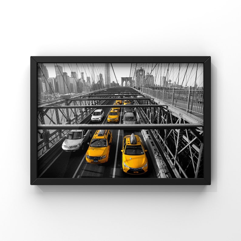May include: A black and white photo of a bridge with yellow taxis driving across it. The bridge is made of metal and has a lot of support beams. The taxis are all facing the same direction and are driving in a line. The city skyline is visible in the background.