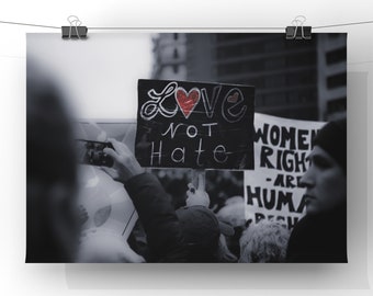 Può includere: Foto in bianco e nero di una protesta con persone che tengono cartelli. Un cartello recita "Love not Hate" con un cuore rosso disegnato su di esso. Un altro cartello recita "I diritti delle donne sono diritti umani".