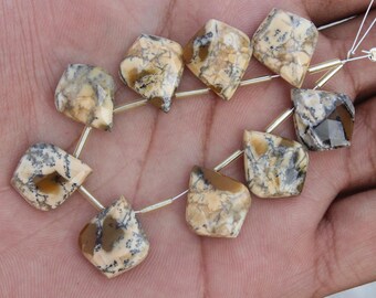 Könnte beinhalten: Eine Kette aus Edelsteinperlen. Die Perlen sind eine Mischung aus beige, braunen und grauen Farben. Jede Perle hat eine einzigartige Form mit einer facettierten Oberfläche. Die Perlen sind auf einem silbernen Draht aufgefädelt, bereit für die Schmuckherstellung.