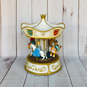May include: A white and gold carousel with a white horse, a tiger, and a princess figure. The carousel is decorated with gold trim and jewels.