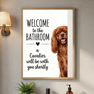 May include: A framed wall print featuring a brown Cavalier King Charles Spaniel peeking from the side. The text reads: WELCOME to the BATHROOM, a Cavalier will be with you shortly. The print includes a small black heart icon between the text lines.