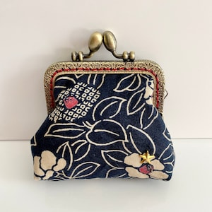 Peut inclure: Une petite bourse à monnaie à motif floral bleu et blanc avec un cadre et un fermoir en métal doré. La bourse a un motif floral rouge et blanc sur le devant.