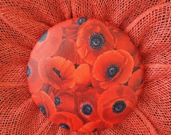 May include: A red mesh wreath with a center made of a red poppy print fabric. The wreath is perfect for a patriotic or summer theme.