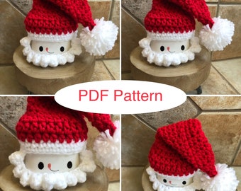 May include: Four crocheted Santa mug toppers in red and white. Each topper features a Santa hat with a white pom-pom and a white beard. The toppers are displayed on wooden coasters. PDF Pattern.