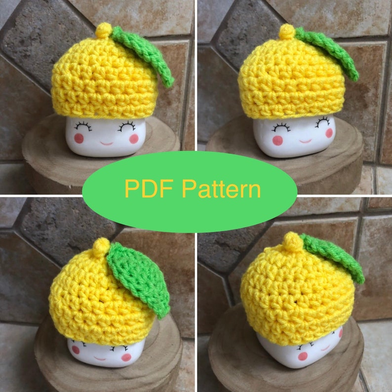 May include: Crochet lemon hat pattern. The pattern is for a yellow crocheted hat with a green leaf on top. The hat is sitting on a white mug with a happy face.
