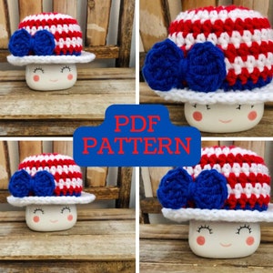Può includere: Un cappello all'uncinetto con strisce rosse, bianche e blu e un fiocco blu. Il cappello è appoggiato su una tazza bianca con un viso sorridente. Il testo "PDF PATTERN" è in lettere rosse su sfondo blu.