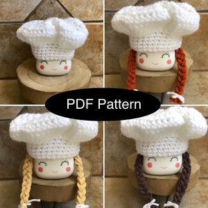 May include: Four crocheted marshmallow chef hats with different colored braids. The hats are white with a white crocheted chef's hat and a smiling face. The braids are orange, brown, yellow, and tan.