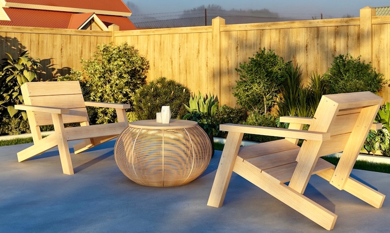 Op de afbeelding: Twee houten stoelen met een gevlochten rieten tafel in een achtertuin. De stoelen zijn gemaakt van licht hout en hebben een eenvoudig ontwerp. De tafel is rond en heeft een gevlochten patroon. De stoelen en de tafel staan op een betonnen terras.