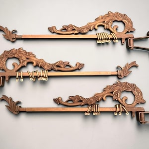 May include: A handmade wooden sign with the text "Welcome" in a playful font. The sign is painted white with a distressed finish, and features a decorative floral design in shades of pink and green. It is designed to be hung on a door or wall.