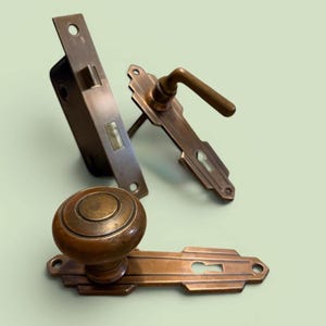 May include: Antique bronze door hardware set, including a door knob, handle, and latch. The set features a classic design with a warm, aged patina. The door knob is round, and the handle has a lever. The latch is rectangular.
