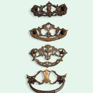 May include: Four antique bronze drawer pulls with ornate designs. The pulls vary in shape and style, showcasing intricate details and aged patina. Ideal for vintage furniture restoration or adding a classic touch to any project.