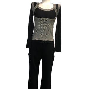 May include: A long-sleeved top and pants set on a mannequin. The top features a black scoop neckline and long black sleeves, with a central panel and shoulder accents in a black and white checkered pattern. The pants are solid black with a flared leg.
