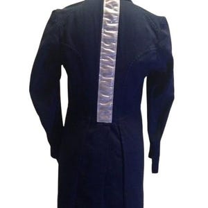 Può includere: Una giacca blu scuro a maniche lunghe con una striscia riflettente bianca sul retro.