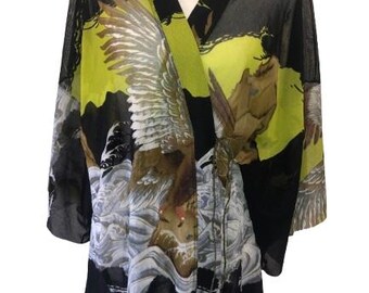 May include: Black sheer kimono with a yellow, green, and brown print of a bird with outstretched wings. The kimono has a long, flowing silhouette and a wrap closure.