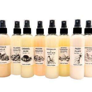 Puede incluir: Colecci&oacute;n de aerosoles corporales en botellas transparentes con tapas negras. Cada botella tiene una etiqueta con un nombre e ilustraci&oacute;n &uacute;nicos, incluyendo "Caramel Musk" y "Marshmallow & White Musk". Las botellas est&aacute;n llenas de l&iacute;quidos de colores.