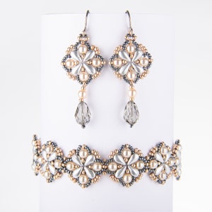 May include: A set of silver and gold beaded jewelry featuring a flower design. The set includes a bracelet and a pair of earrings with crystal drops.