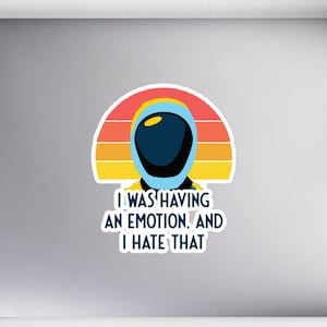 May include: A sticker with a retro-style illustration of an astronaut with the text "I was having an emotion, and I hate that."