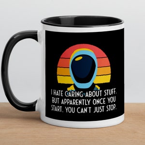 May include: White ceramic mug with a black rim and handle. The mug features a retro-style sunset graphic with a cartoon astronaut in a blue and white spacesuit. The text on the mug reads: "I hate caring about stuff. But apparently once you start, you can't just stop."